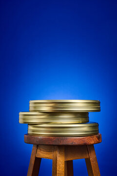 Close-up of a collection of analog film canisters on a wooden stool, against a blue background.