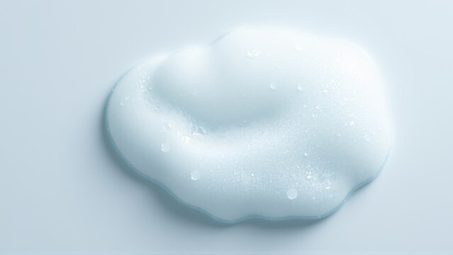 Light blue foam blob. Soft texture visible, droplets present. Minimalist studio shot, clean background. Focus on product consistency.