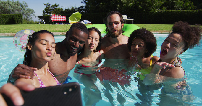 Diverse group of friends having fun taking a selfie in swimming pool