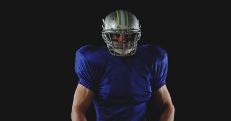 Portrait of caucasian male american football player in helmet and blue shirt, copy space on black © WavebreakMediaMicro