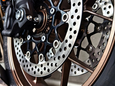 Motorcycle front wheel with perforated brake disc and caliper hardware