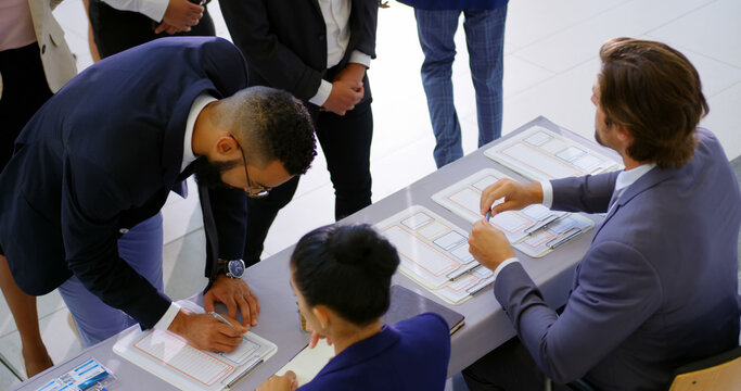 Business professionals queue for conference check-in captured from above in 4K.