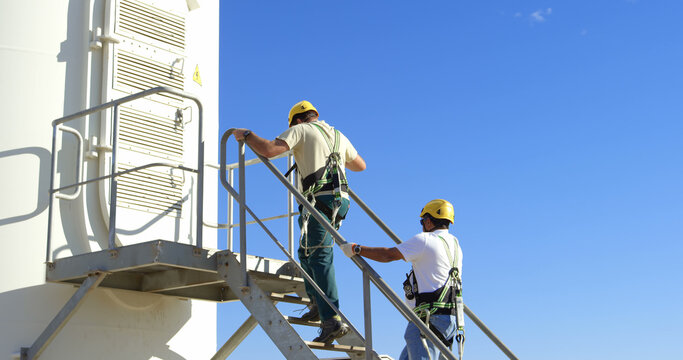 Professionals in safety gear climb a staircase at an industrial site, indicating expertise.
