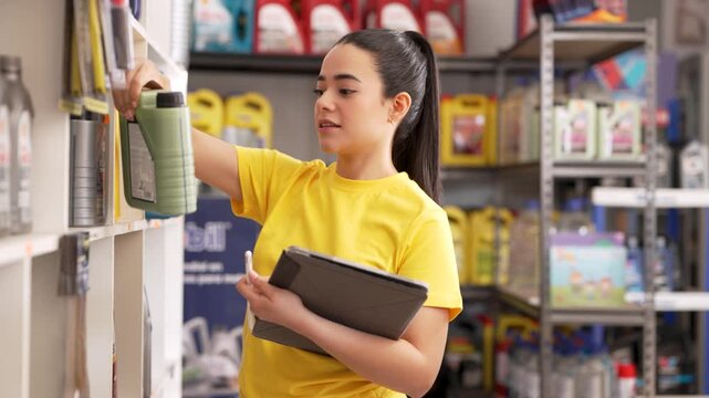 Young latina woman inventorying automotive products with tablet computer while working in auto shop