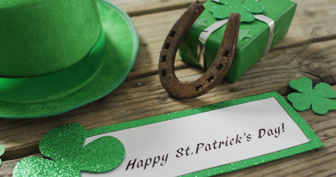 Happy st patricks day text with shamrocks and green hat with copy space on wooden table