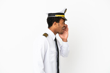 African American Airplane pilot over isolated white background shouting with mouth wide open to the lateral © luismolinero