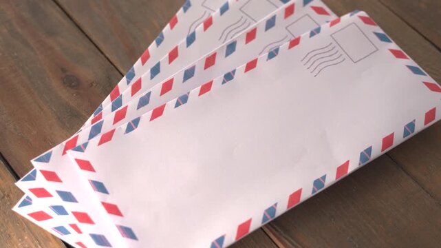 Fan of Four Airmail Envelopes with Red and Blue Striped Borders on Wooden Table