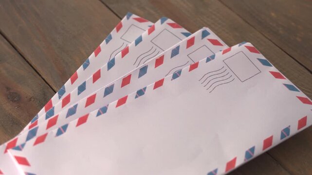 Fan of Four Airmail Envelopes with Red and Blue Striped Borders on Wooden Table