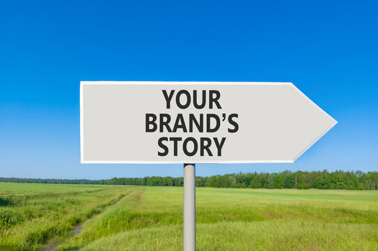 Branding and your brands story symbol. Concept words Your brands story on beautiful grey road sign. Beautiful blue sky green grass background. Business branding your brands story concept. Copy space