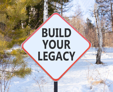 Build your legacy words symbol. Concept words Build your legacy on beautiful white road sign. Beautiful winter forest background. Business build your legacy concept. Copy space.