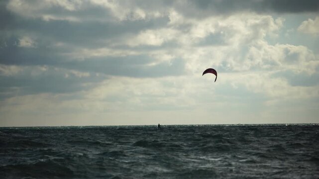 Kiteboarding, Ocean, Clouds - A single kitesurfer sails across a choppy ocean under cloudy skies.