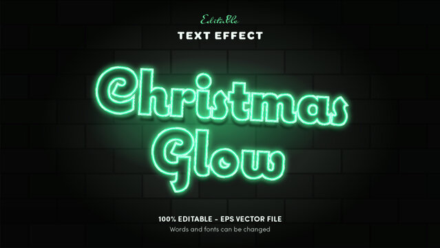 Editable Christmas neon sign text effect, emerald-green glass tube script with green halo on a dark brick wall