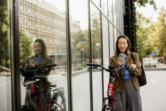 Korean woman pauses with her electric bike beside a glass building