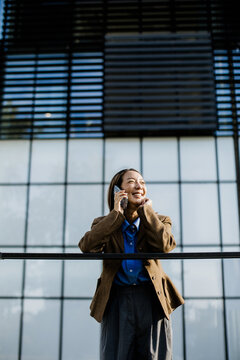 Woman talking on phone near a modern building in bright daylight
