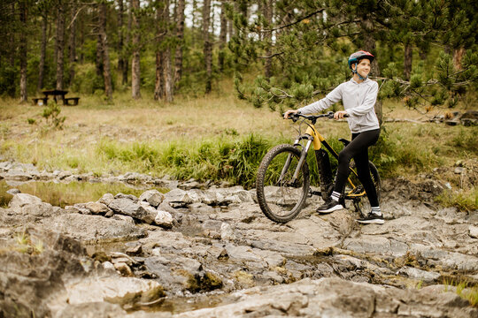 E bike rider pauses beside a rocky forest stream