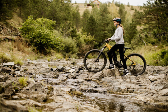 Rider pauses with an e bike on a rocky woodland trail