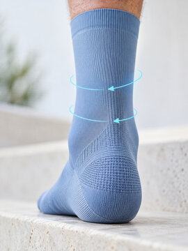 Close-up of compression sock on ankle with pressure arrows. Graduated compression hosiery for circulation support. Medical foot care and vascular health. Therapeutic apparel for leg comfort.