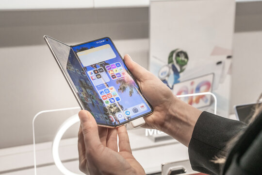 Moscow, Russia, 28 09 2026:  Woman holding partially folded Huawei Mate X7 smartphone showing flexible touchscreen and folding design in an electronics store