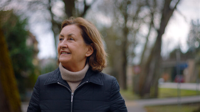 Joyful Caucasian senior woman laughing while walking in the park, carefree happiness and zest for life