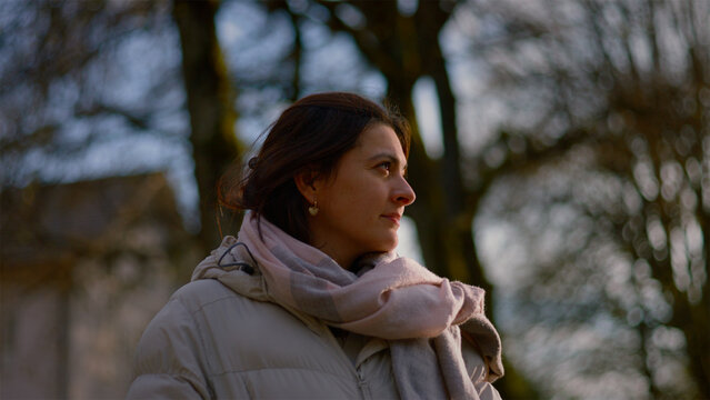 Young Caucasian woman standing in a sunlit winter park looking around, hope and fresh beginnings