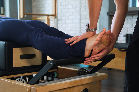 Personal trainer supporting the feet during resistance work - wide view