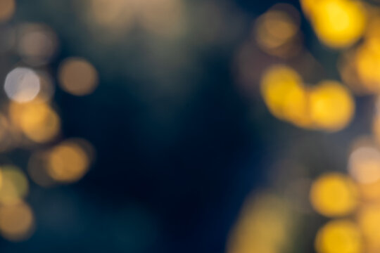 Abstract autumn background with blurred golden yellow birch leaves, warm amber bokeh lights and deep blue tones, creating a soft seasonal nature backdrop with copy space.