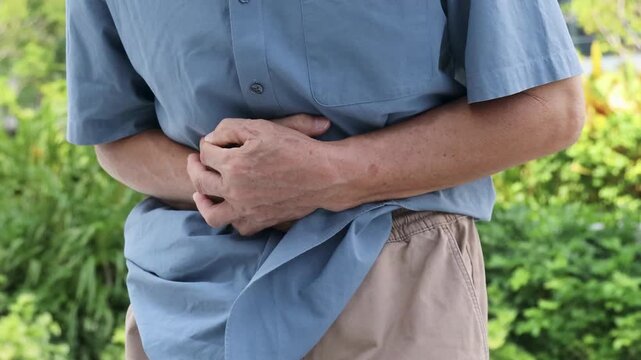 Hand of 60s old senior asian man holding stomach with pain from stomachache