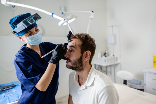 Woman doctor marking male patient for hair transplant procedure