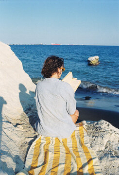 Reading by the Beach With the Ocean in the Background