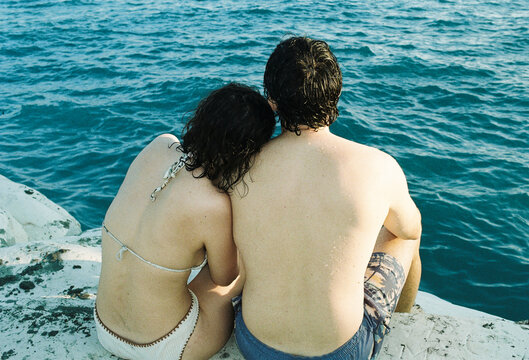 Couple Sitting by the Water, Enjoying Time Together