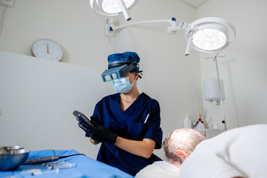 Specialist performing hair transplantation procedure on male patient
