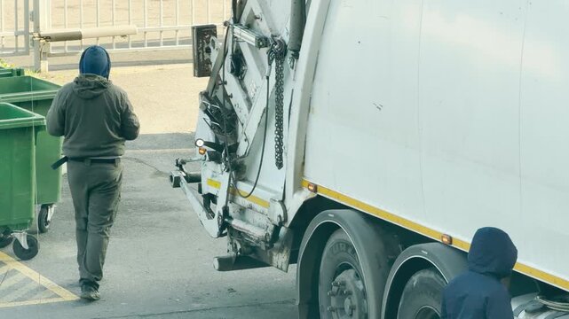 Sanitation workers collect trash beside a garbage truck on a street in Pushkin, Russia. The focused routine highlights diligence and a sense of calm duty.