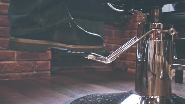 Barber foot pumping hydraulic chair pedal. Closeup barbershop boot low angle.