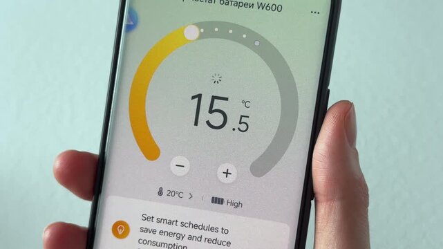 Lowering temperature for energy saving in thermostat app. Heating off and electricity economy to reduce bills. Smart home finger control for eco savings..