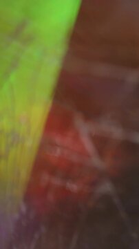 Vertical video. Defocused light overlay. Film flare. Crackled rotation yellow red green abstract prism glow. Optical colorful reflection background.