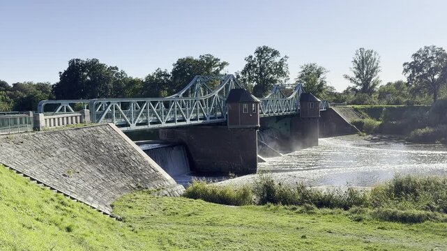 Historic steel truss river dam and weir structure across Oder River under clear blue sky in Wroclaw Poland, industrial engineering heritage and water management infrastructure video footage clip