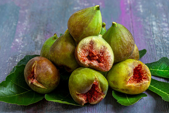 Fresh Figs on Leaves Stacked on a Wooden Surface