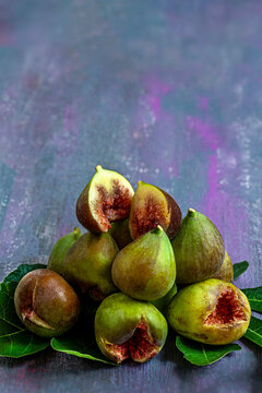 Figs Arranged on a Surface With Green Leaves