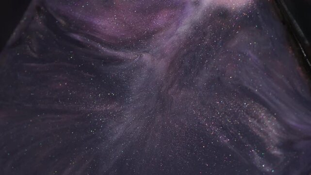Splatter water. Fluid spill. Defocused purple color glitter paint stone particles sparking floating on abstract art background.
