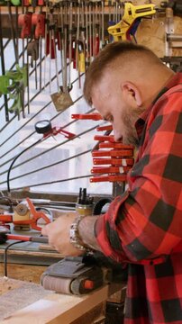 Vertical video. Woodworking process. Lumber industry. Man polishing plank with professional sander. Carpenter occupation with diy project workshop.