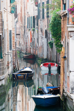 Venice canal with boats along narrow waterway between brick buildings