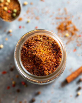 Top view professional cookbook photography of Lebanese seven spice powder (baharat), warm reddish-brown spice powder in a small glass jar, minimal elegant 