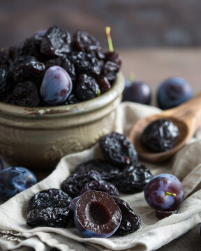 Rustic food photography of dried plums and fresh plums, prunes spilling from a glass jar