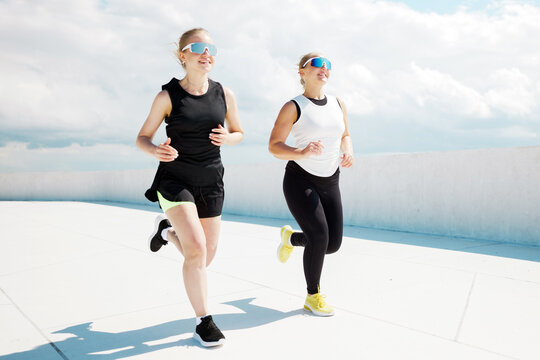 Two women enjoying a lively run on a bright sunny day with a picturesque sky