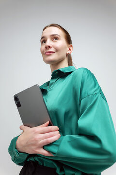 Confident woman in green shirt holding a tablet with a smile