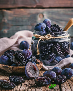 Rustic food photography of dried plums and fresh plums, prunes spilling from a glass jar