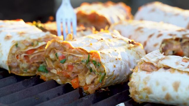 Minced meat and vibrant vegetables wrapped in lavash are perfectly grilled. The cooking process enhances the flavors while achieving a golden, crispy exterior, inviting you to take a bite.