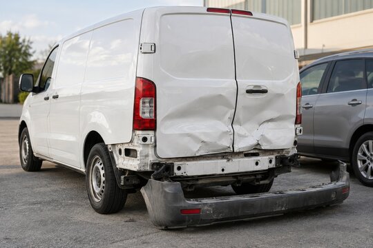 White Delivery Van with Dented Rear Doors and Detached Bumper