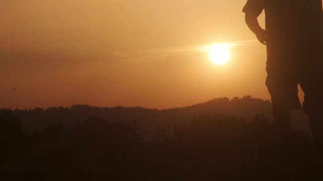 Silhouette of a man walking across the landscape during golden sunset light, celebrating the summer solstice in asturias
