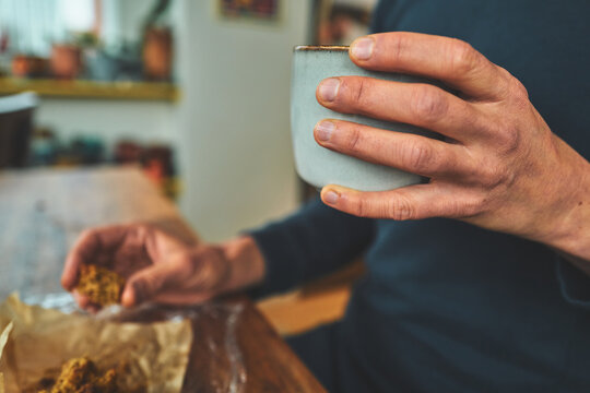 Woman Holding a Tea Cup While Reaching for a Piece of Cake
